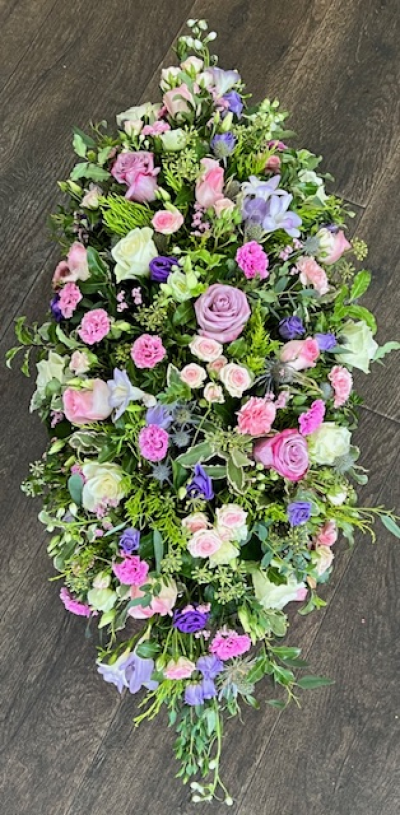 Casket spray pastel - elegant funeral casket spray, arranged in soothing pastel tones - soft shades of pink, lavender, ivory and peach, are thoughtfully blended with complimentary greenery.