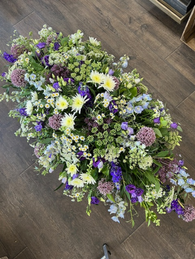 Casket spray country - country style casket spray features a natural meadow-inspired design with a soft comforting palette of purples, whites and gentle greens, overflowing with wild, garden like charm.