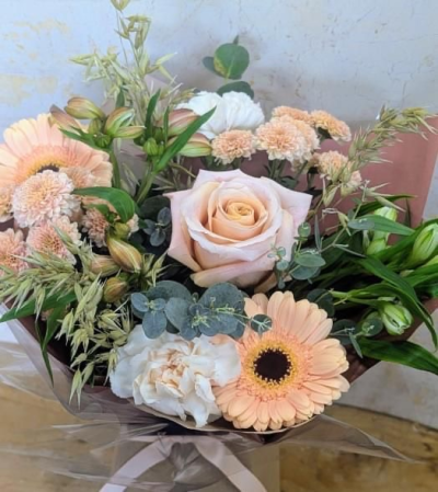 Harvest Blush - A gentle embrace of soft amber, blush, and ivory tones, this bouquet captures the warmth of autumn’s fading sunlight.  Its mix of rounded blooms, ruffled textures, and earthy greenery creates a rustic yet elegant charm.  The arrangement feels like a stroll through golden fields at dusk,  where the air is crisp and the season whispers of comfort and abundance.