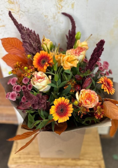 Rustic Ember - A rich gathering of fiery orange,  golden amber, and deep russet tones,  this bouquet carries the warmth of a countryside harvest.  With layers of rustic textures and woodland greenery, it evokes the glow of falling leaves, the crackle of a fire, and the simple beauty of autumn days spent close to nature.