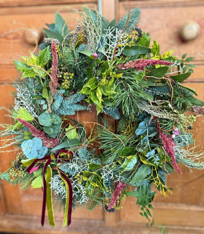 The Wildwood wreath - Bring the charm of a winter countryside walk to your door with our Woodland Forager’s Christmas Wreath. This handcrafted design is brimming with texture and natural beauty—featuring fragrant evergreen sprigs, variegated holly, soft eucalyptus, frosted-looking lichen, and clusters of winter berries. Deep burgundy amaranthus adds a rich, rustic accent, paired with velvet ribbons that create a warm, nostalgic finish.

A celebration of the season’s wild greenery, this wreath captures the cosy spirit of a country Christmas—earthy, abundant, and beautifully untamed. Perfect for welcoming guests with a touch of woodland magic.
