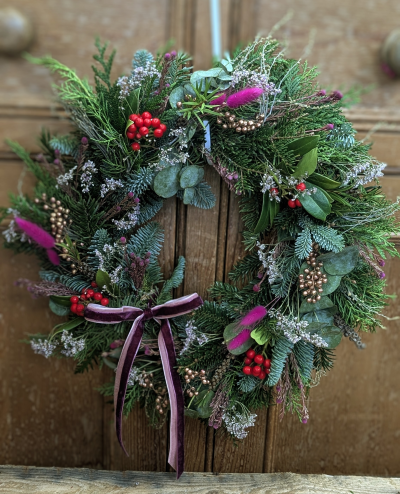 The Sugarplum magic Wreath - A celebration of winter’s quiet abundance, this wreath gathers the scents, colours, and textures of the countryside at Christmastime. Lush evergreens mingle with soft, wild sprigs and bright woodland berries, while touches of bronze and velvet add a whisper of festive magic. Each element curls and weaves like hedgerows in midwinter, capturing the gentle stillness of the season and offering a warm, welcoming glow to any door.