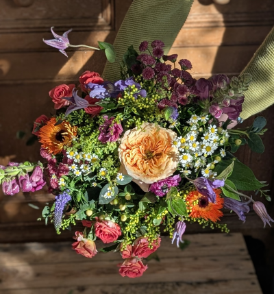 Countryside love - This Mother’s Day bouquet captures the heartwarming charm of a country garden in full bloom. At its center, a glowing apricot focal bloom draws the eye, surrounded by a joyful harmony of coral, blush, lavender, deep berry, and vibrant tangerine tones.

Airy white accents add a light, meadow-like softness, while textured blossoms and fresh greenery create a naturally gathered, just-from-the-field feel. The arrangement is abundant yet relaxed — full of warmth, colour, and thoughtful detail.

Rustic, romantic, and brimming with character, this bouquet is a beautiful tribute to Mum — celebrating her nurturing spirit, strength, and the love that makes a house feel like home.

Please note: While the overall country-inspired style, colour palette, and fullness will remain consistent, individual varieties and shades may vary depending on seasonal availability. Any substitutions will be carefully chosen to maintain the bouquet’s overall look and feel.