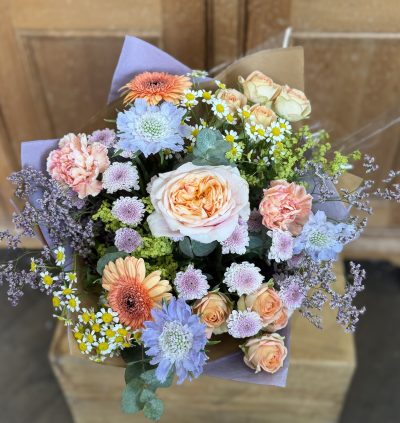 Peachy Skies - A joyful, garden-inspired bouquet bursting with soft peach, blush, lilac and powder blue tones. Delicate textures and airy accents create a relaxed, whimsical feel, while the warm peach tones bring a touch of sunshine and playful charm.

Please note: The colour palette and overall style of this design will remain the same, but the specific flowers and foliage may vary depending on seasonal availability.